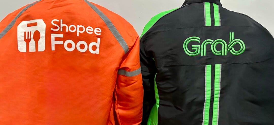 Dua pengemudi ojek online dari ShopeeFood dan Grab saat sedang menunggu pesanan. (Foto Oleh: Michelle Arletta, 21 Mei 2025)