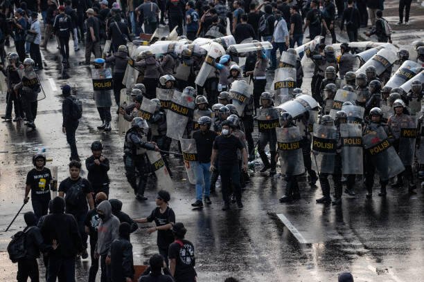 SURABAYA, INDONESIA - MARCH 24: Activists clash with Indonesian Police officers during a protest against the military law revision on March 24, 2025 in Surabaya, Indonesia. On March 20, Indonesia's House of Representatives passed a revision to military law, allowing military officers to serve in more government posts and take up civilian positions without resigning from the Indonesian National Armed Forces. This amendment has drawn criticism from civil society groups, who warn it could signal a return to the repressive New Order era under former President Soeharto, when military officers dominated civilian affairs.Critics argue that this change could lead to abuse of power, human rights violations, and political impunity for army personnel, reminiscent of the era under dictator Suharto, who stepped down in 1998. The timing is particularly significant as Indonesia is now led by President Prabowo Subianto, an ex-special forces general and former son-in-law of Suharto, who was inaugurated in October 2024. (Photo by Robertus Pudyanto/Getty Images)
