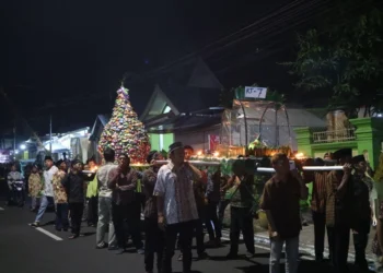 “Masyarakat sedang mengikuti prosesi arak-arakan tumpeng untuk memperingati 1 Suro, sebagai wujud syukur dan pelestarian budaya lokal.”
