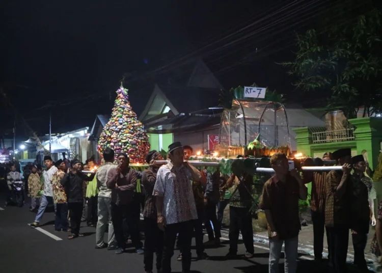Kirab Tumpeng: Kolaborasi Mahasiswa UB dan Masyarakat Desa Bokor 1 “Masyarakat sedang mengikuti prosesi arak-arakan tumpeng untuk memperingati 1 Suro, sebagai wujud syukur dan pelestarian budaya lokal.”
