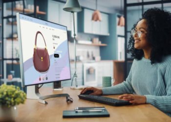 Latina Female Using Desktop Computer with Clothing Online Web Store to Choose and Buy Clothes from New Collection. Female Browsing the Internet at Home Living Room while Sitting at a Table