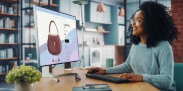 Latina Female Using Desktop Computer with Clothing Online Web Store to Choose and Buy Clothes from New Collection. Female Browsing the Internet at Home Living Room while Sitting at a Table