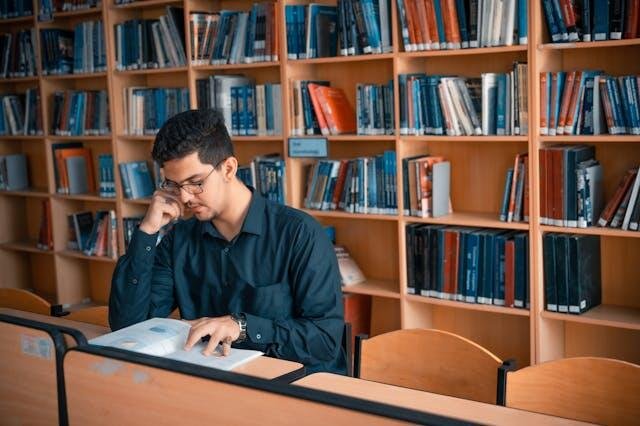 a focused student studying intently amidst the quiet solitude of a library surrounded by shelves of books as they diligently work on an architectural research paper