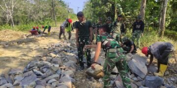 Anggota Satgas TMMD Ke-129 Kodim 0601/Pandeglang bersama masyarakat mengangkat dan menyusun batu untuk pengerasan jalan desa di Kecamatan Patia, Kabupaten Pandeglang, pada hari ke-11 pelaksanaan TMMD.