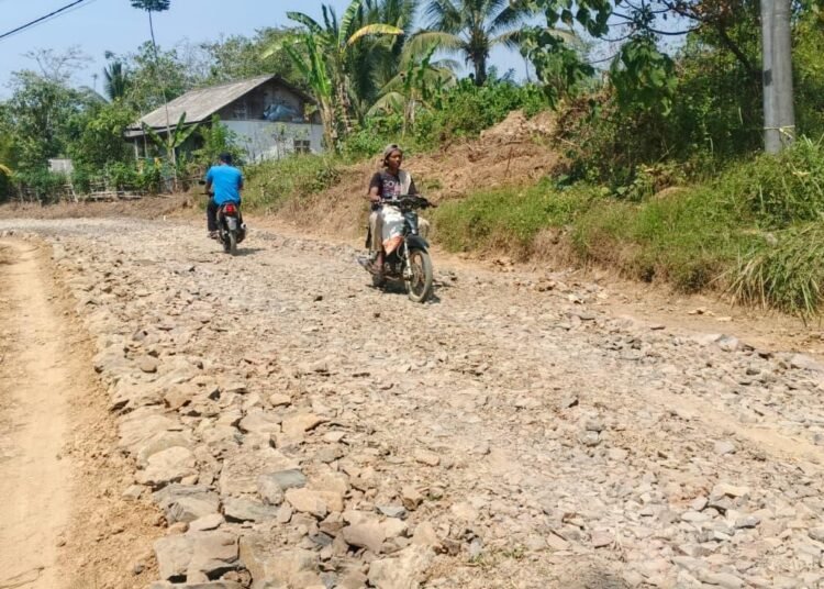 Warga Desa Pasirgadung melintasi jalan hasil pengerasan Program TMMD Ke-129 Kodim 0601/Pandeglang di Kecamatan Patia, Kabupaten Pandeglang, yang kini mulai dimanfaatkan untuk memperlancar aktivitas sehari-hari.