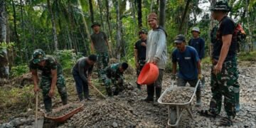 Personel Satgas TMMD Ke-129 Kodim 0601/Pandeglang bersama warga Desa Pasirgadung dan Desa Simpangtiga bergotong royong mengangkut batu serta mengerjakan pembangunan jalan di Kecamatan Patia, Kabupaten Pandeglang, Kamis (30/7/2026).