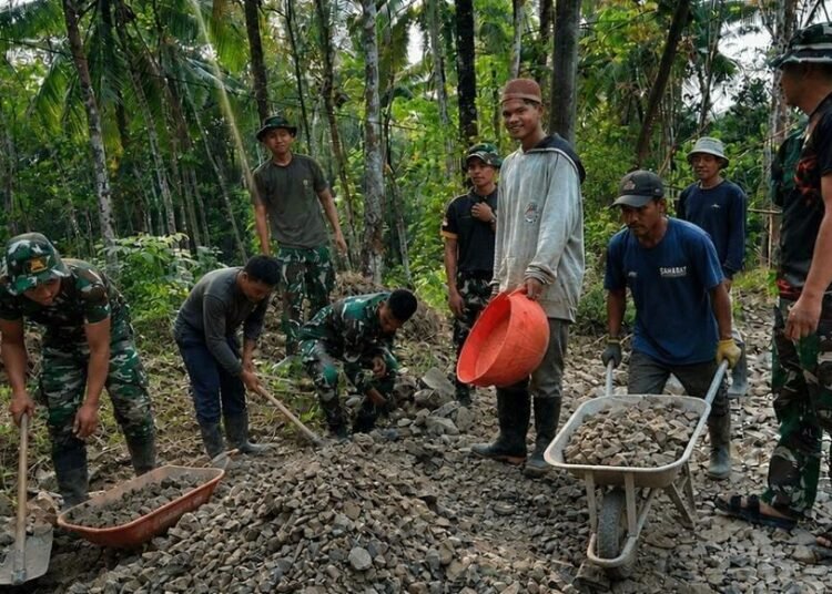 Senyum Warga di Balik Tumpukan Batu, Inilah Wajah Humanis TMMD Ke-129 5 Personel Satgas TMMD Ke-129 Kodim 0601/Pandeglang bersama warga Desa Pasirgadung dan Desa Simpangtiga bergotong royong mengangkut batu serta mengerjakan pembangunan jalan di Kecamatan Patia, Kabupaten Pandeglang, Kamis (30/7/2026).