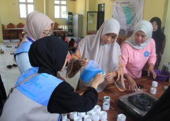 Perwakilan PKK Desa Sedayu didampingi mahasiswa KKN UIN Walisongo Posko 173 saat menuangkan lilin cair ke dalam cetakan.(Foto: Dok. KKN)