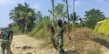 Personel Satgas TMMD melaksanakan pembersihan rumput dan semak belukar di sekitar tenda posko guna menciptakan lingkungan yang bersih, aman, dan nyaman selama pelaksanaan Program TNI Manunggal Membangun Desa (TMMD).