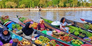 Aktivitas jual beli di Pasar Terapung Siring Banjarmasin, Kalimantan Selatan, dengan para pedagang menggunakan perahu untuk menjajakan beragam hasil pertanian dan kebutuhan sehari-hari di atas Sungai Barito. (Sumber: https://www.linkedin.com/)