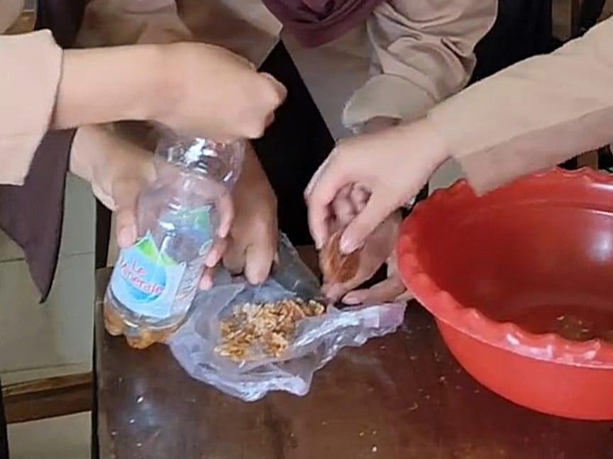 (Siswa memotong gula dan memasukkan gula yang telah dipotong ke dalam botol, kemudian mengocoknya hingga gula larut sebagai bagian dari proses pembuatan eco-enzyme. Dokumentasi pribadi)