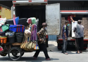 Seorang pedagang perabotan rumah tangga keliling mendorong gerobaknya. Keterbatasan modal usaha dan ketergantungan pada pendapatan harian membuat pekerja di sektor ini sangat rentan terhadap guncangan ekonomi.